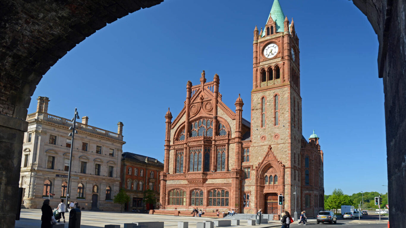 Majestic red-brick guildhall with a clock tower; guests enjoy cultural charm and vibrant surroundings.