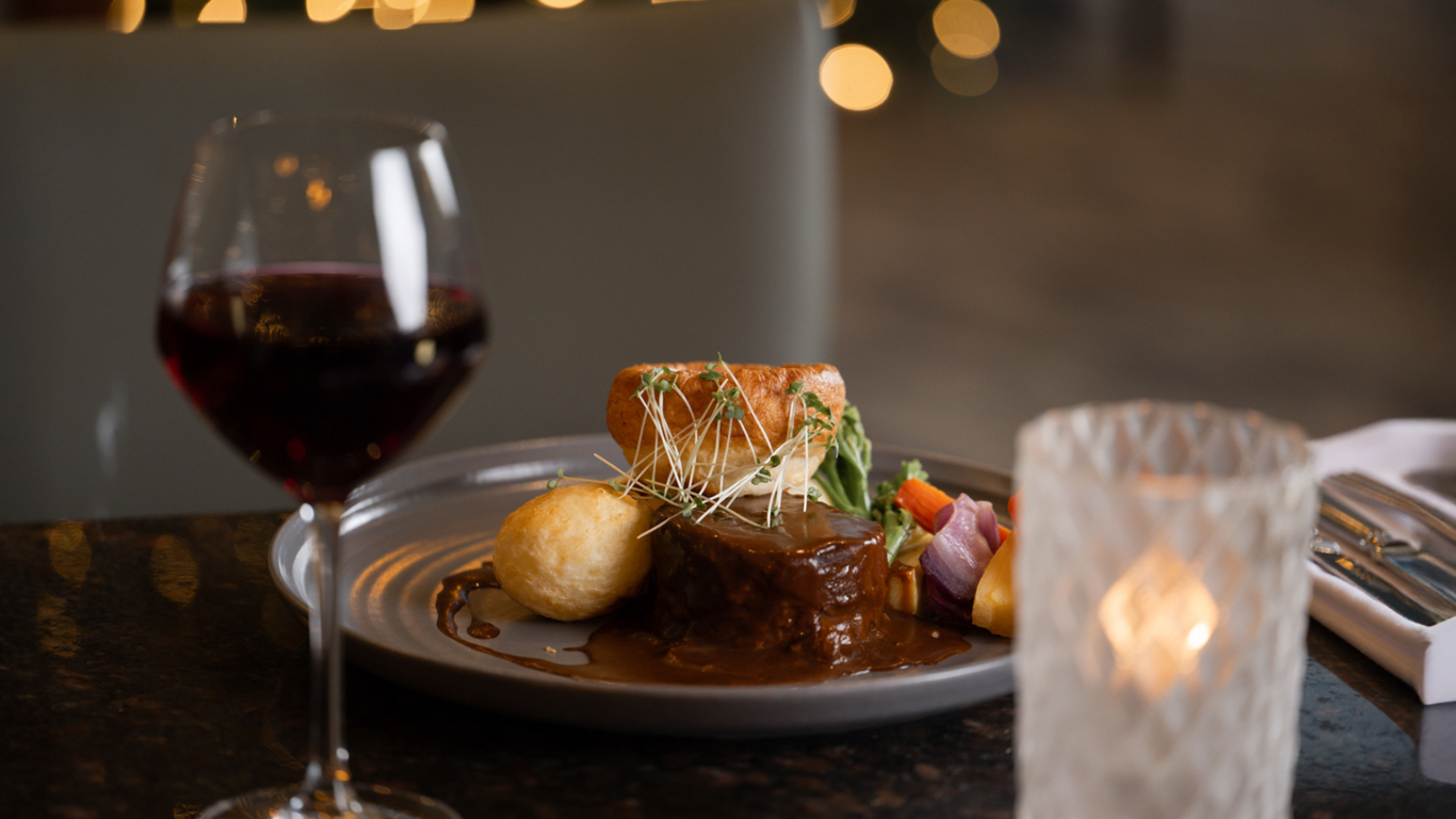 Elegant hotel dining with gourmet meal, wine, and romantic candlelight, offering a luxurious culinary experience.