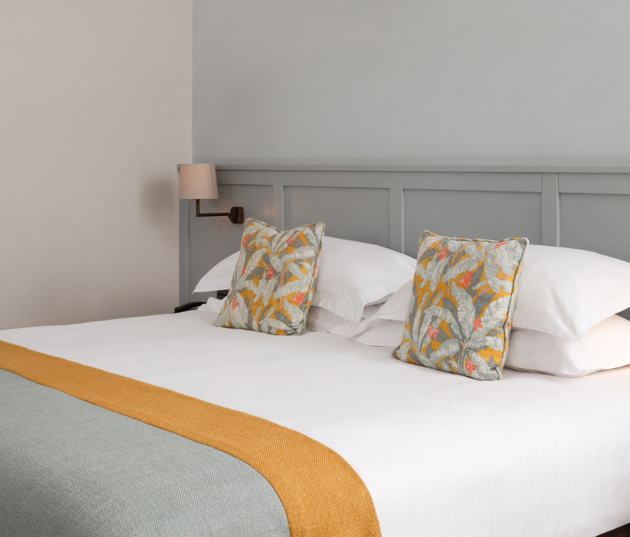 Elegant hotel room with king-size bed, plush bedding, soft lighting, and stylish decor offers a serene escape.