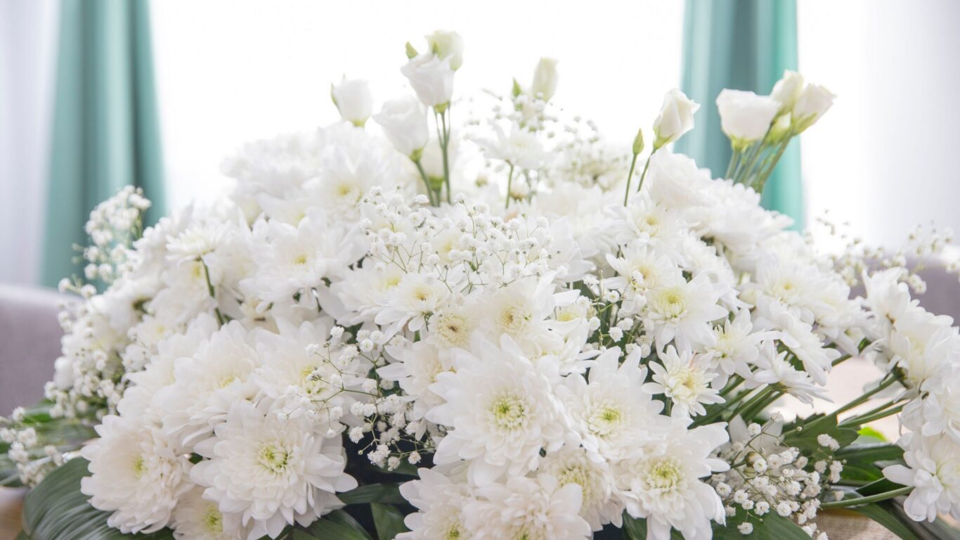 Elegant white flower arrangement with greenery in hotel lobby, offering guests a welcoming, serene atmosphere.
